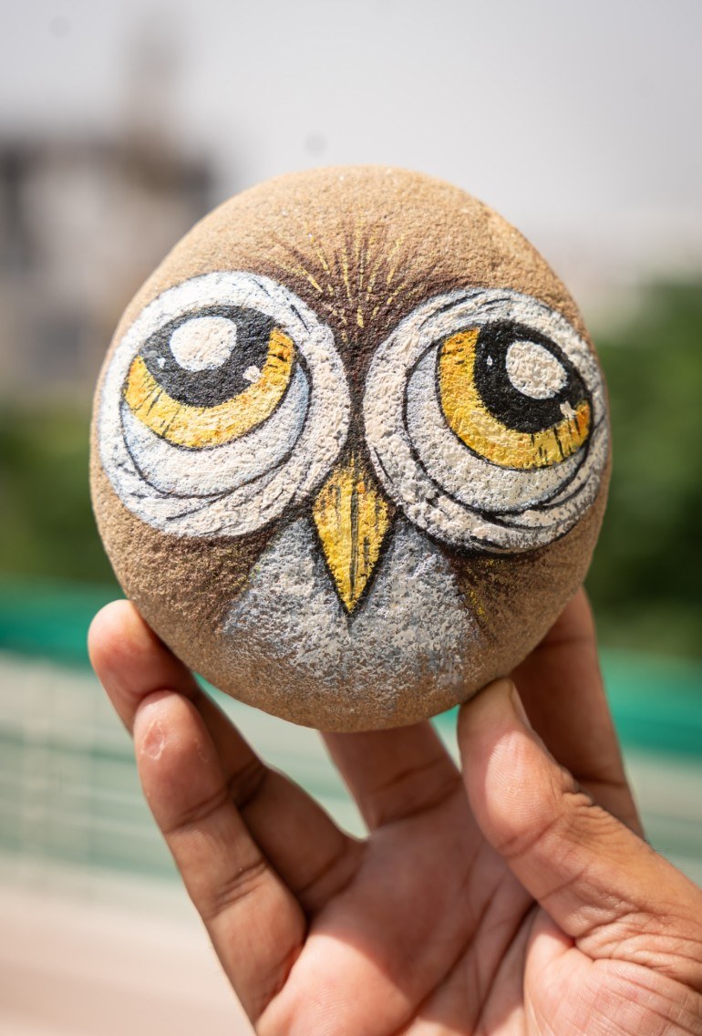 Owl face painted on a round stone