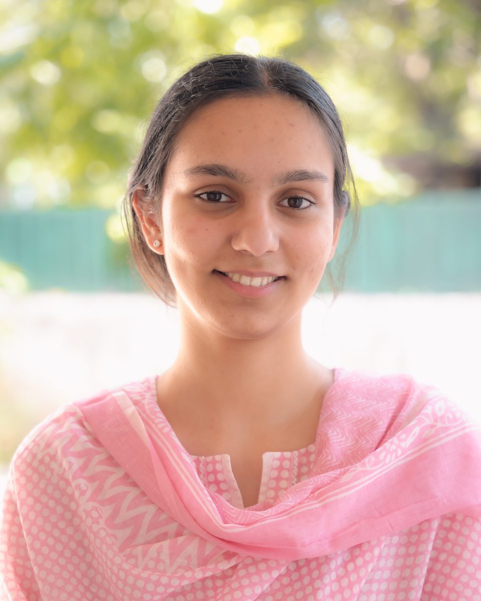 Eknoor Kaur Sandhu, smiling outdoors under trees